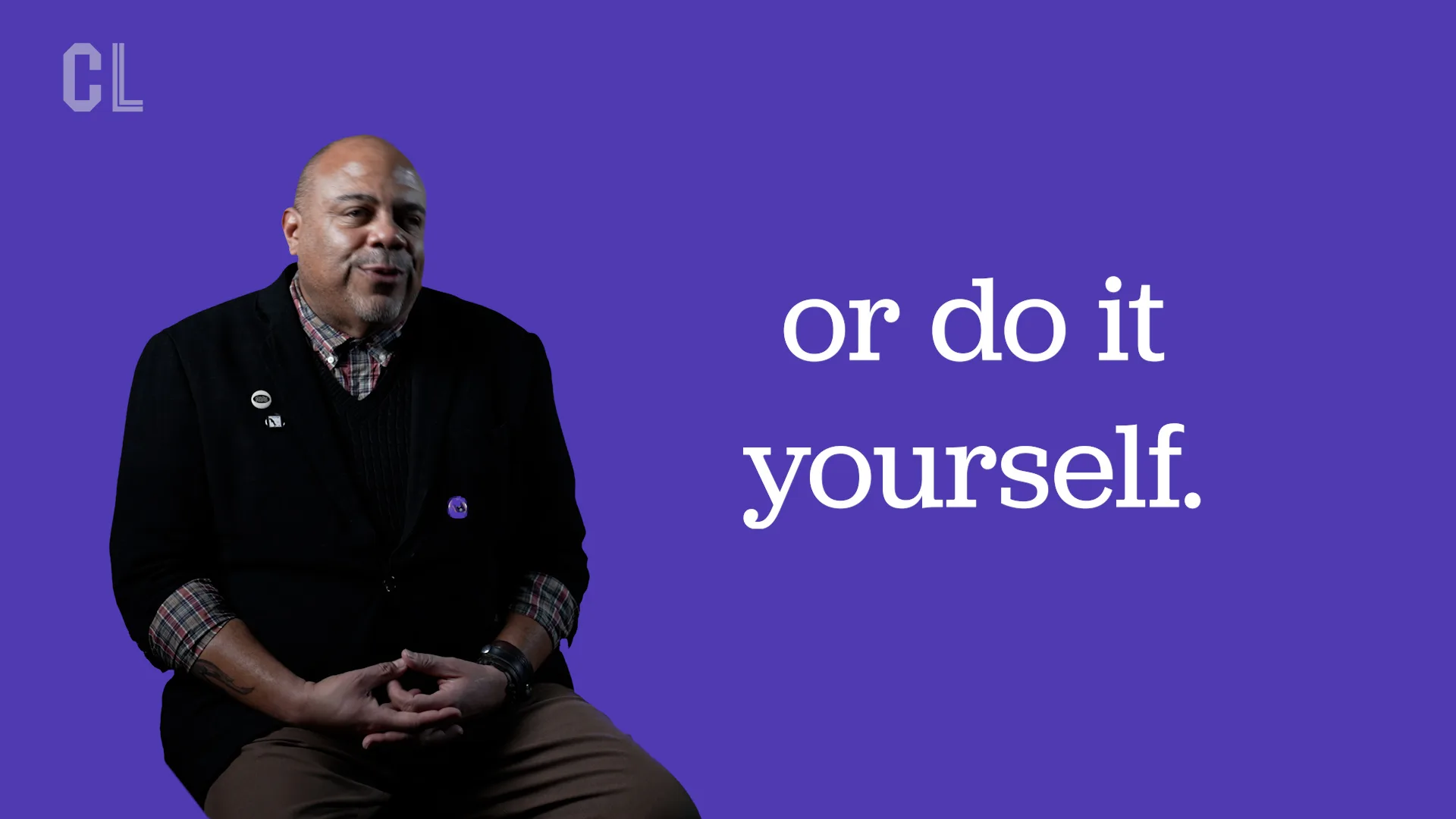 A person in a black sweater sitting with their hands in their lap in front of a purple backdrop with the words "or do it yourself"