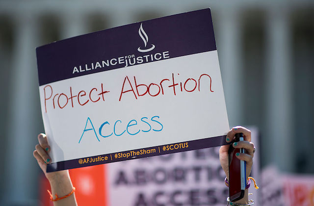 A person holds a protest sign that reads, "Protect Abortion Access"