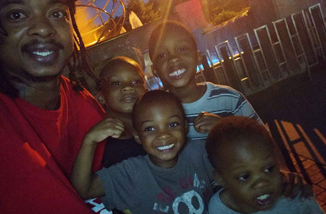 Jacob Blake and children. Black man with locs wearing red shirt in photo with four young Black boys.