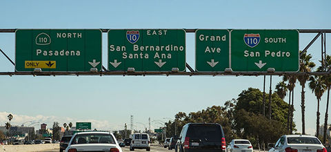 Rideshare strike. Interstate signs for 110 North (Pasadena) - 10 East (San Bernardino, Santa Ana), Grand Avenue, and 110 South (San Pedro).