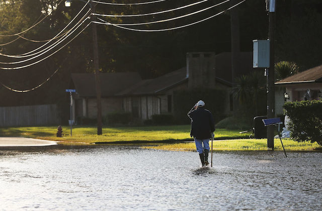 An outdoor shot of a Black man walking through flooded streets towards a house
