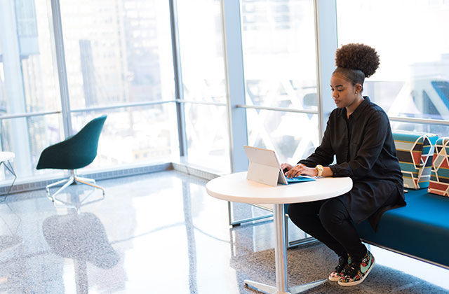 PayPal Black Latinx business. Young Black woman with pomp pomp Afro at a desk and laptop.