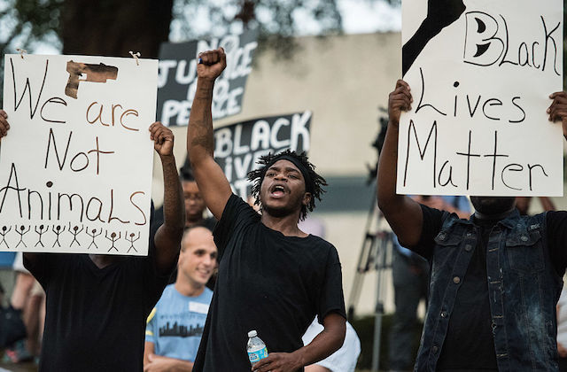 Young Black men hold up signs that read "We are not animals" and "Black lives matter."
