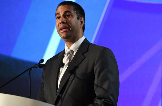 Brown man in navy suit in front of blue digital screen