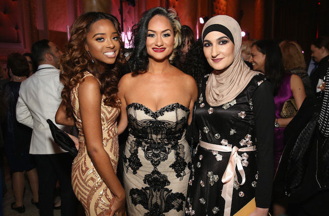 Three women in fancy dresses pose for a photo at a gala