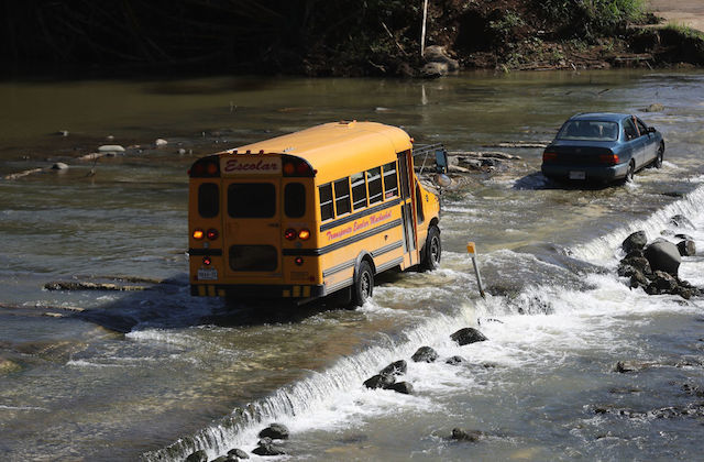A school bus crosses a makeshift automobile bridge, after the original bridge was washed away during Hurricane Maria flooding, on December 20, 2017 in Morovis, Puerto Rico.