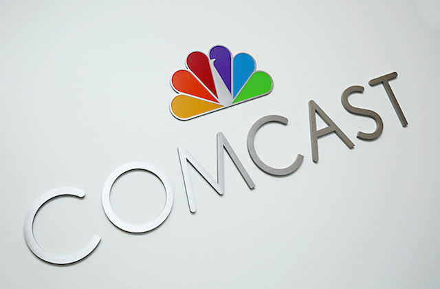Silver letters spell "COMCAST" under multicolored NBC logo on off-white background
