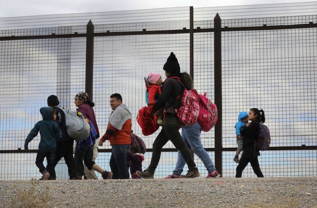 A group of Central American families, including men, women and children, are bundled up in colorful, warm clothing as they walk along the border fence after crossing the Rio Grande from Mexico on February 01, 2019.