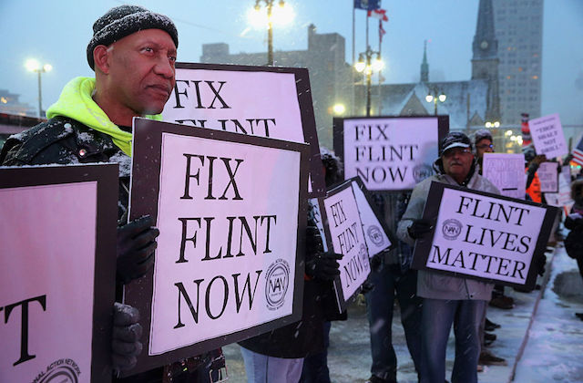Black protestors holding signs to fix Flint 