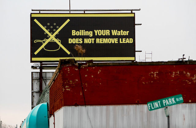 Black and yellow billboard in Flint, Michigan, reads, "Boiling your water does not remove lead."