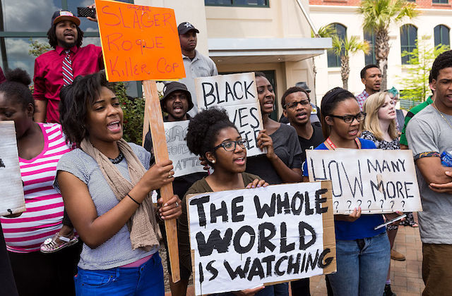A group of Black women and men hold signs protesting the death of death of Walter Scott, who was killed by police in a shooting, outside City Hall in North Charleston, South Carolina, on April 8, 2015. 