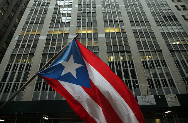 Red, white and blue Puerto Rican flag in front of a high rise office building 