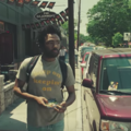 Donald Glover in shirt reading "keep on keeping on" while walking on street