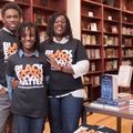 A Black man and a Black woman pose with a pre-teen Black child in a bookstore