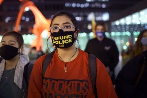 Image of woman wearing "defund police" face mask