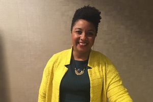 Black and Latina woman with yellow jacket and short curly hair