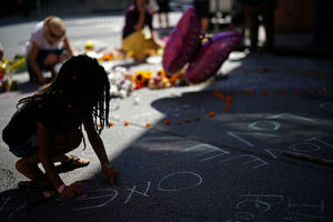 Black girl writes on ground using chalk