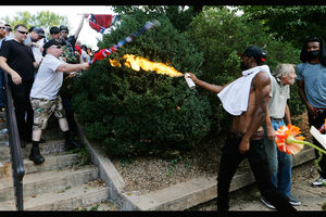 Black man in black pants with white shirt and black hat stands next to White man and Black man holds white can with orange flames at White men in black and white clothing holding red and white and blue Confederate flags