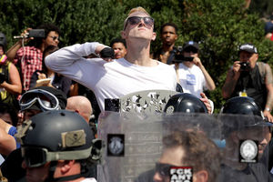 A White man in sunglasses and a White shirt makes a slashing motion across his neck during the "Unite the Right" rally in Charlottesville, Virginia