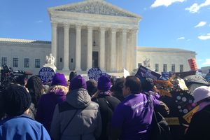 A crowd of people stands before the Supreme Court building.