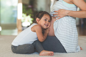 Little girl listens to a pregnant woman's belly