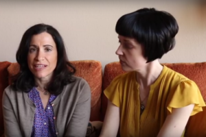 Two women sit next to each other on a couch